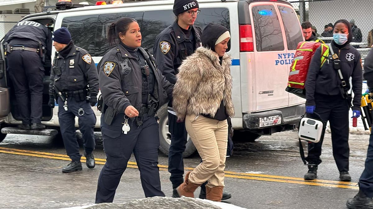 Migrant in handcuffs being led by NYPD police