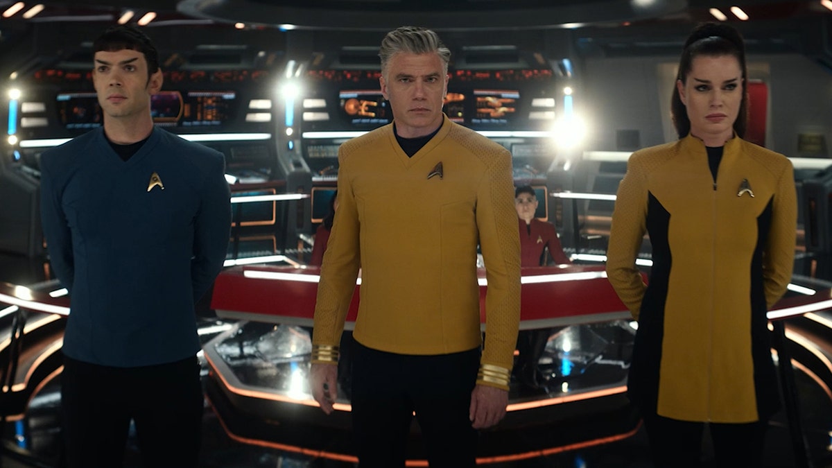 Ethan Peck, Anson Mount and Rebecca Romijn in blue and yellow Star Trek uniforms