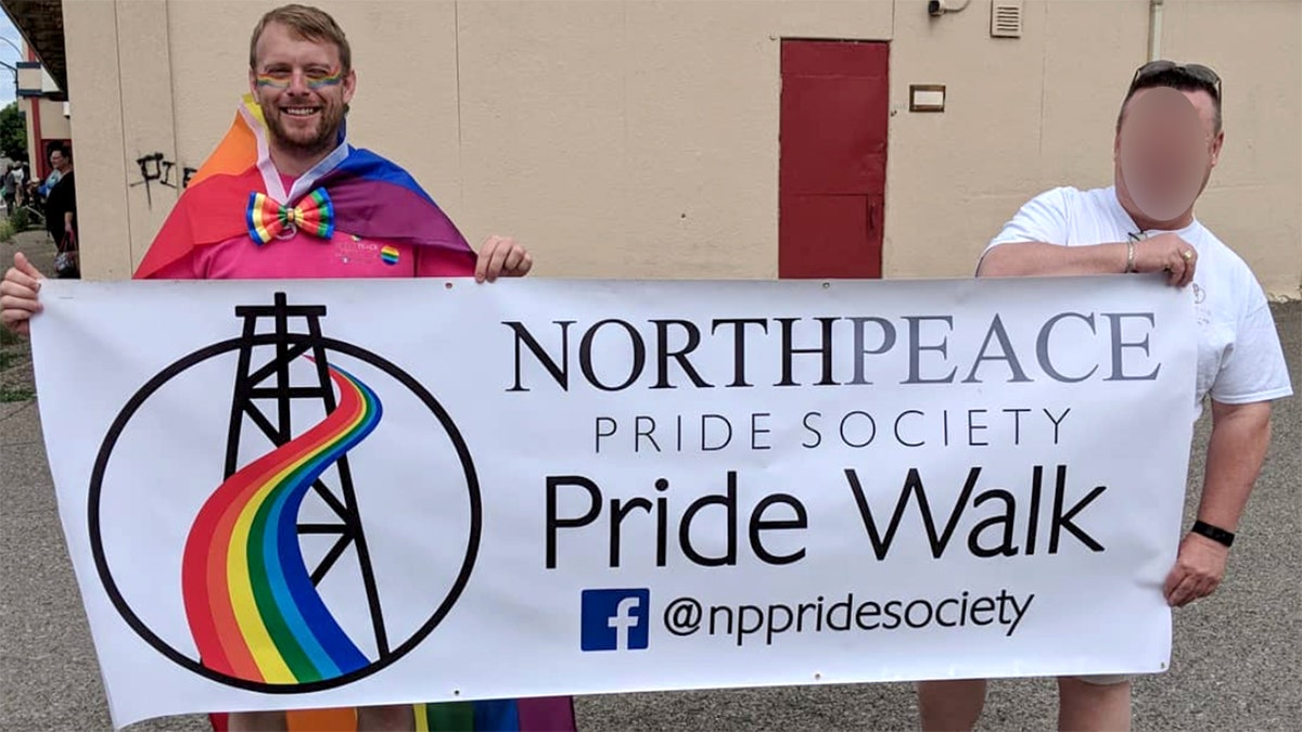 Gravells posing with a pride banner