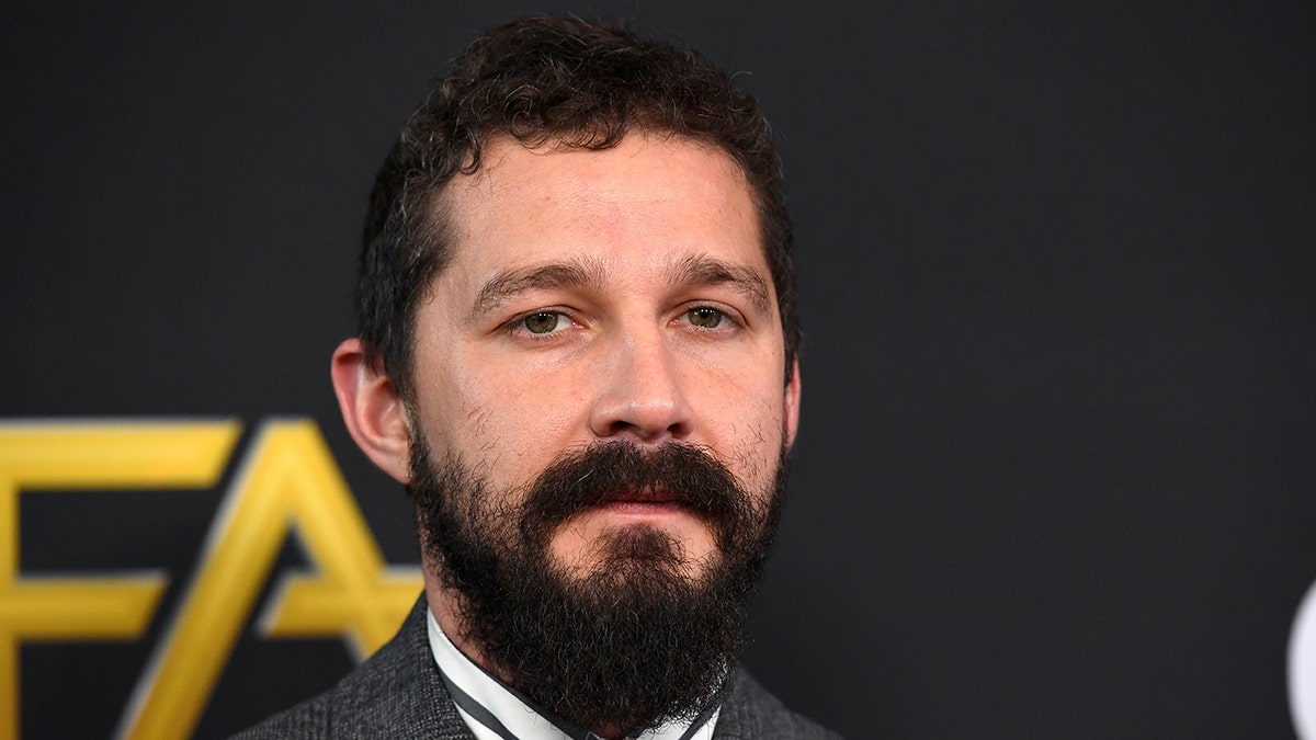 Shia LaBeouf looks serious on the carpet with a thick beard and mustache