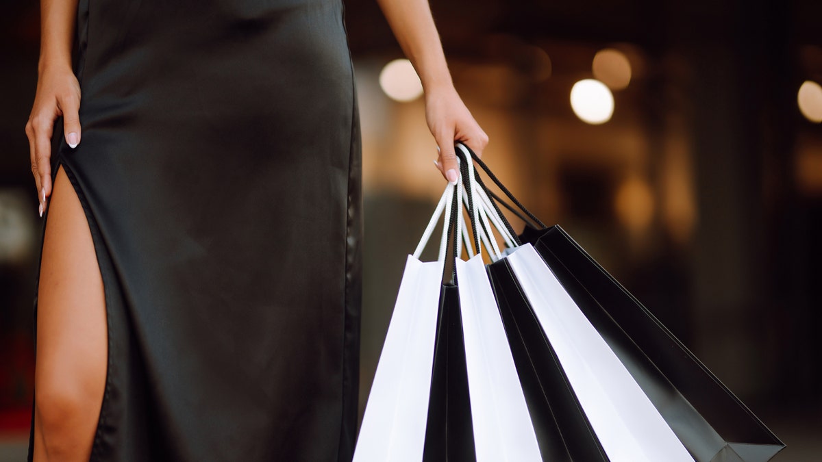 woman in black dress holding shopping bags
