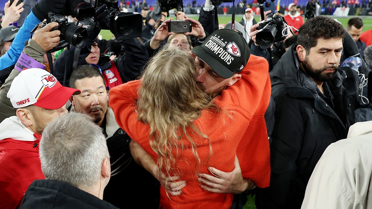 Travis Kelce hugs and kisses Taylor Swift on the field after Chiefs win