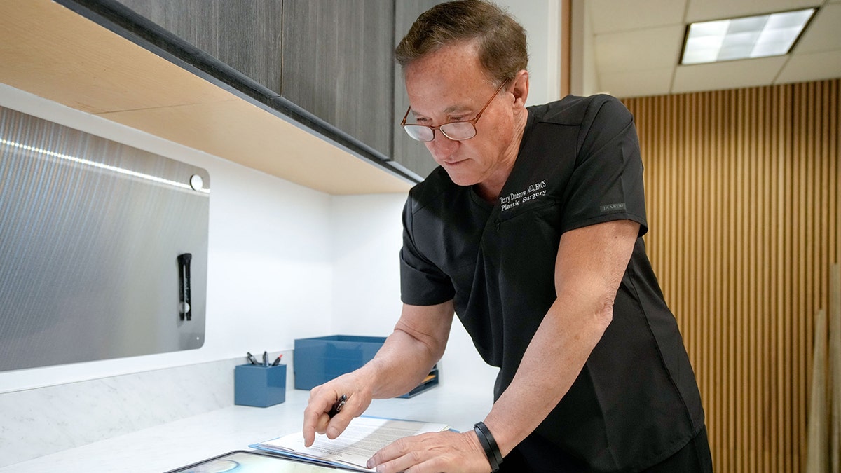Terry Dubrow working with an ipad in a medical office