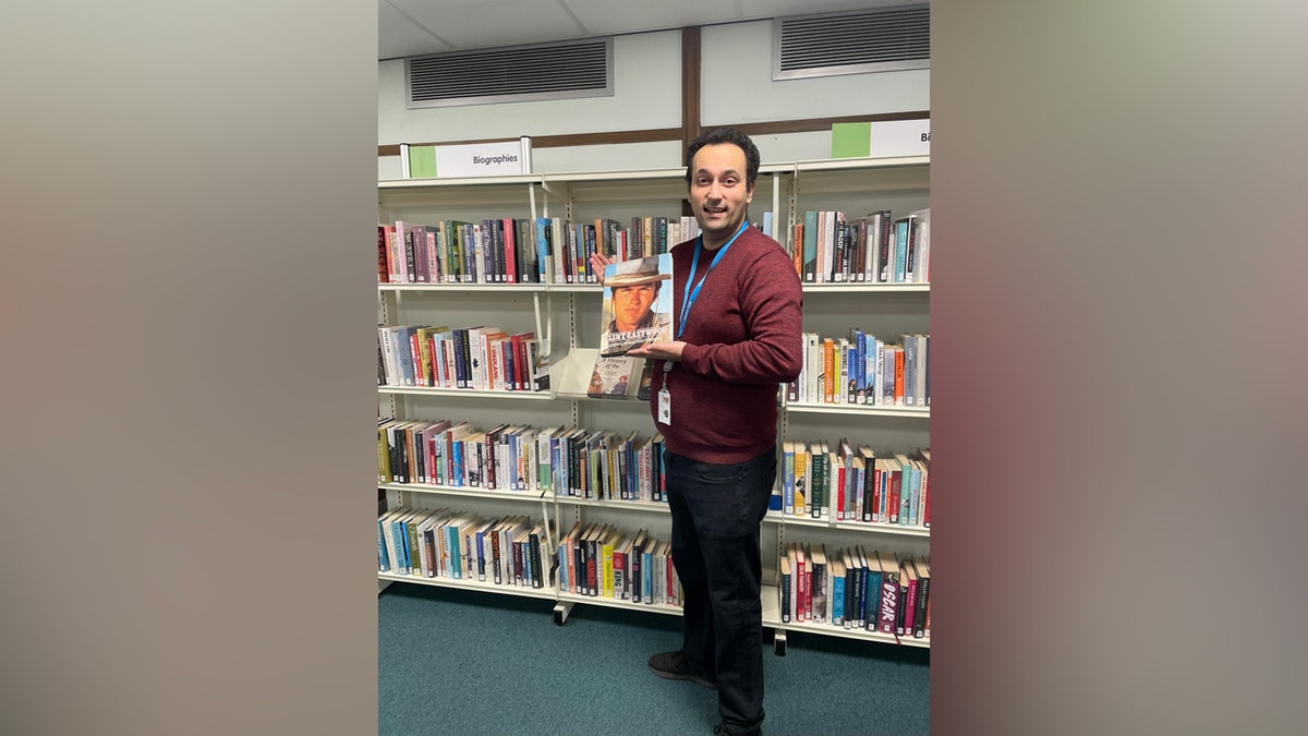 Wide shot of library employee holding long-lost book