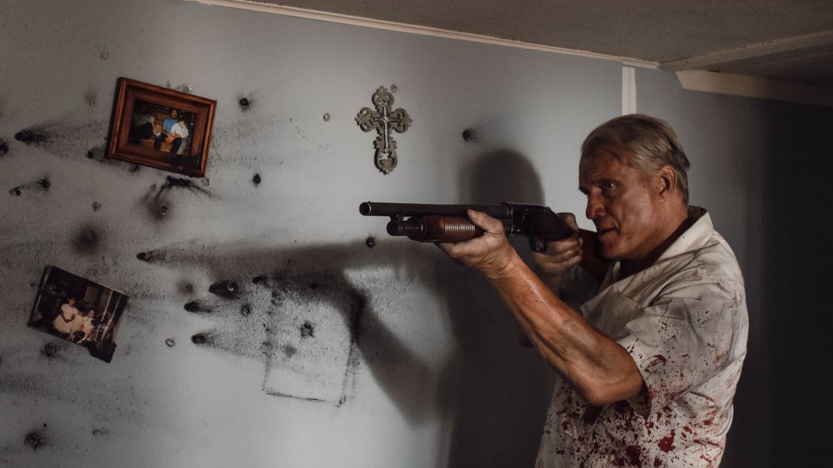 dolph lundgren holding a gun in blood-splattered clothes in wanted man