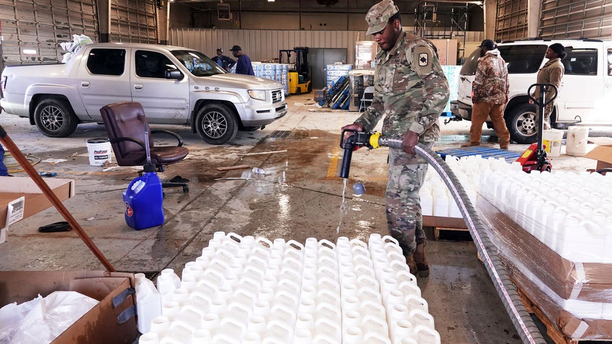 Jonathan McDowell, a member of the National Guard, prepares water jugs to be distributed to people without running water on Jan. 30, 2024, in Helena, Arkansas. 