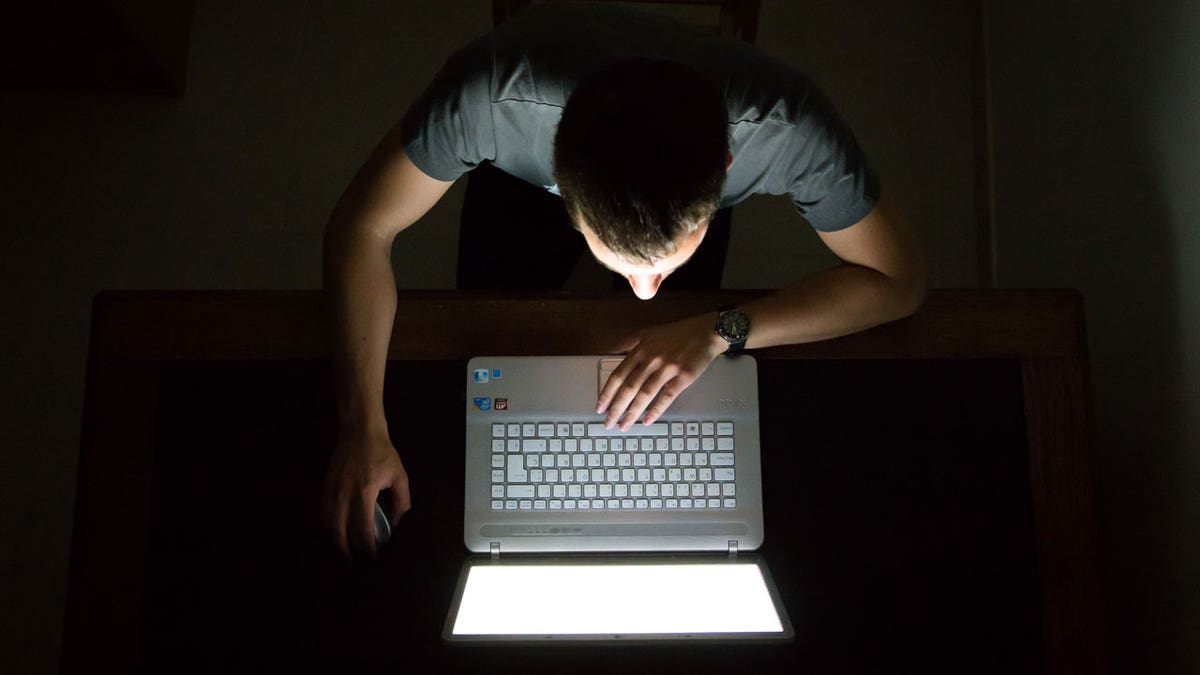 Guy checking internet with laptop at late night with dark room, view from above.