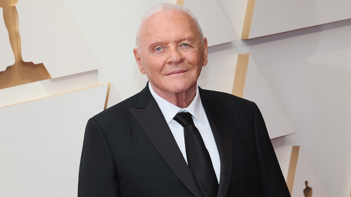 Anthony Hopkins in a black suit and tie on the carpet at the Academy Awards