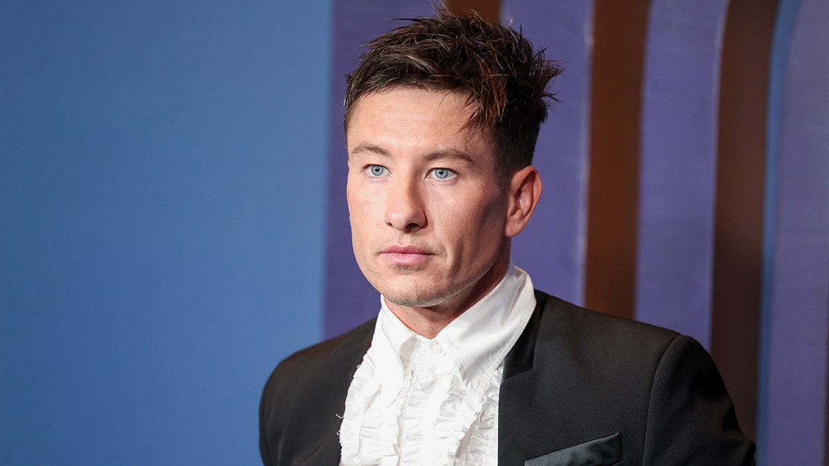 Barry Keoghan looks stoic on the carpet in a white button down and black jacket
