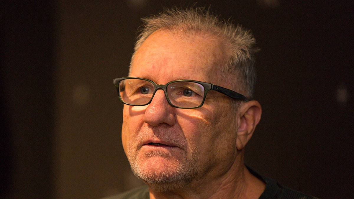 Ed O'Neill looks off in the distance with black frame glasses on