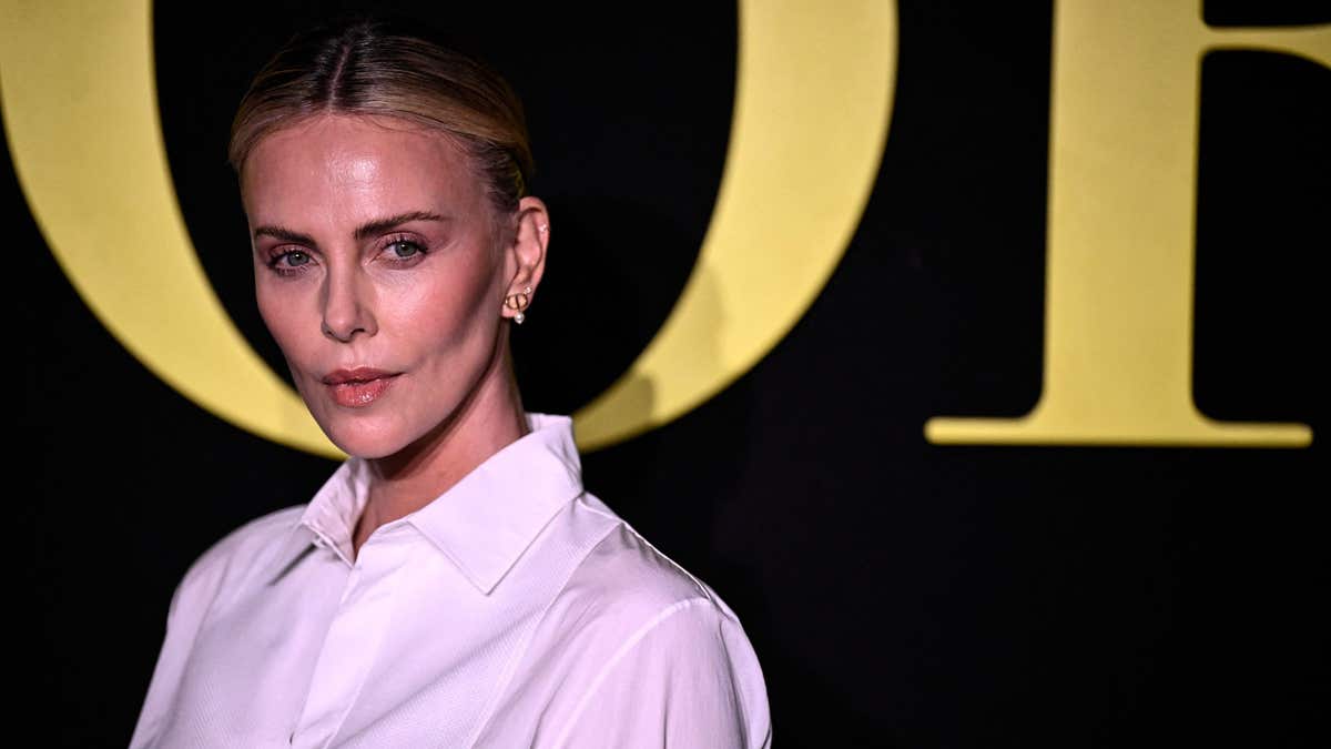 Charlize Theron poses ont he carpet in a white blouse