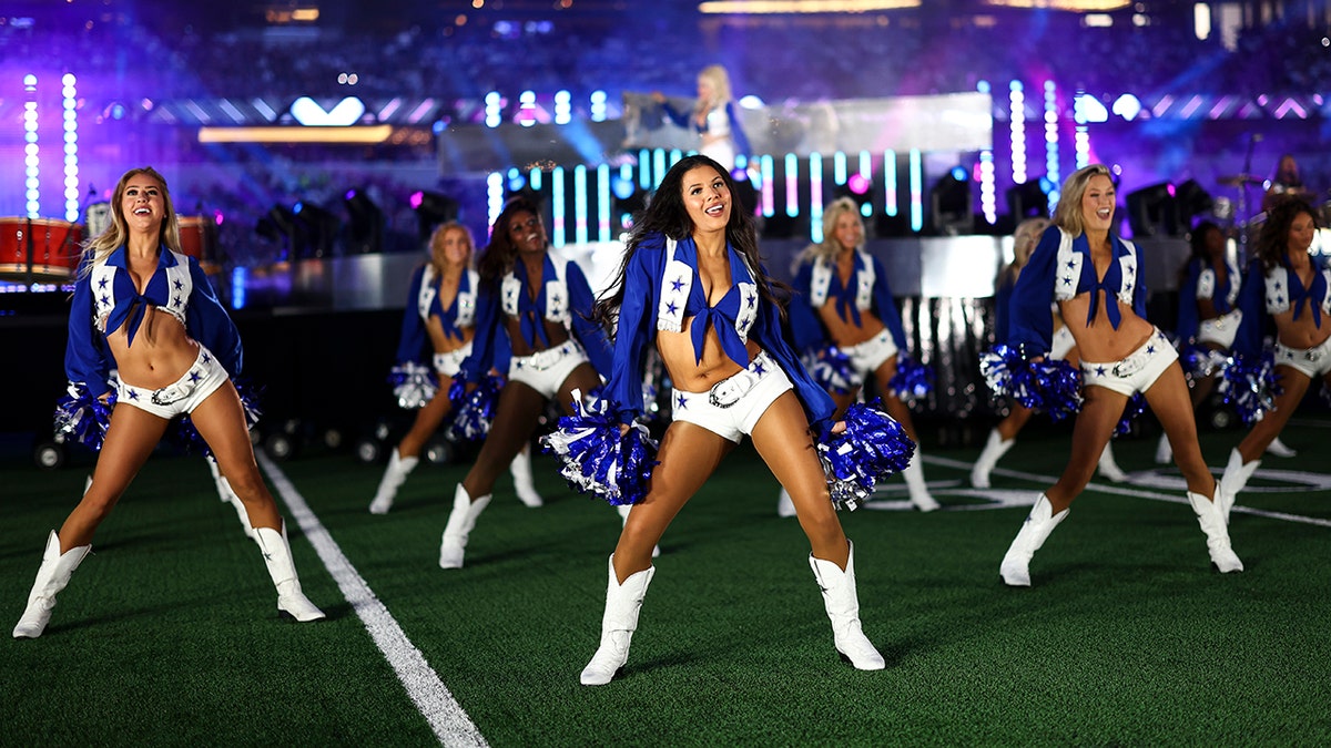 Dallas Cowboys cheerleaders dance on the field with Dolly Parton performing in the background