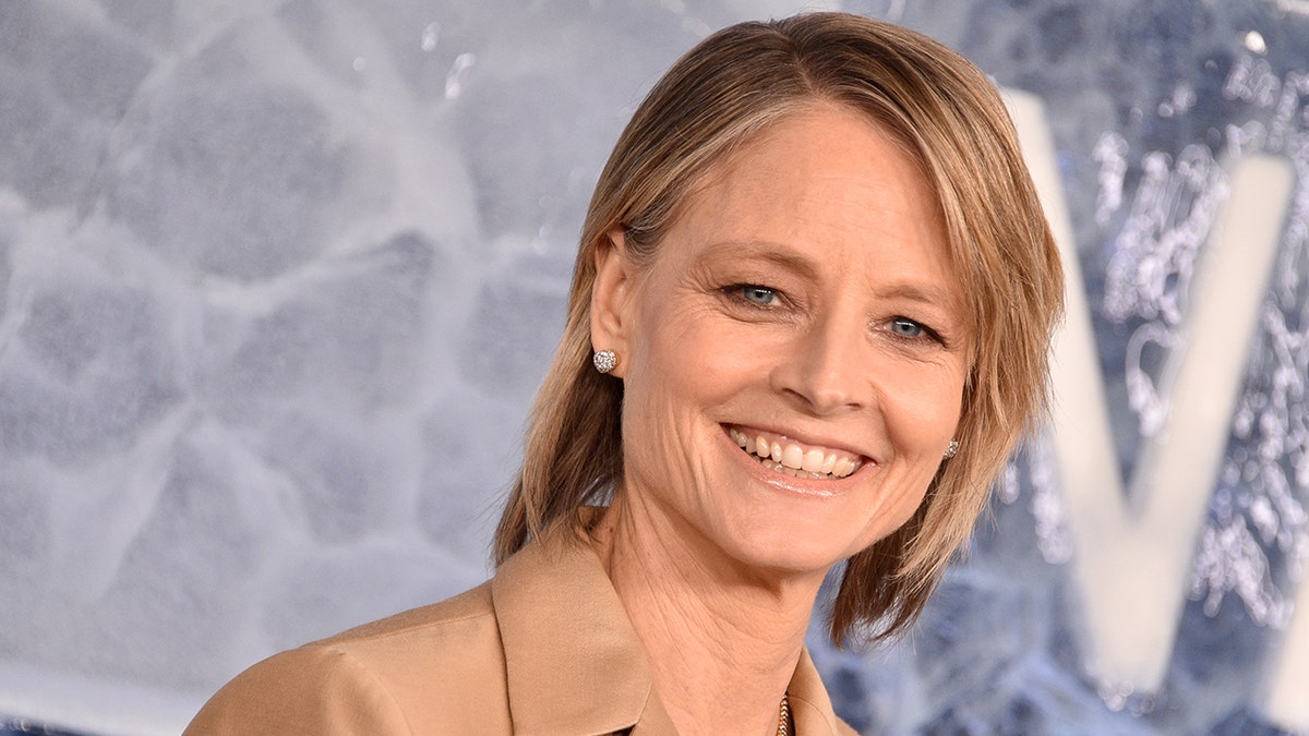 Jodie Foster smiles in a tan blazer on the carpet