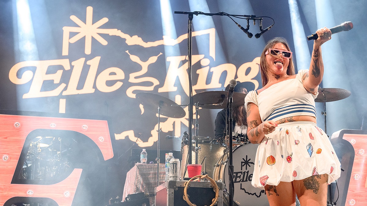 Elle King in a white floral skirt and white top performs on stage in Florida