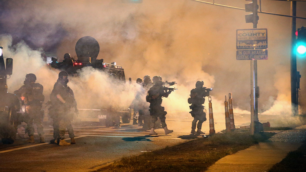 riot police amid clouds of smoke, tear gas