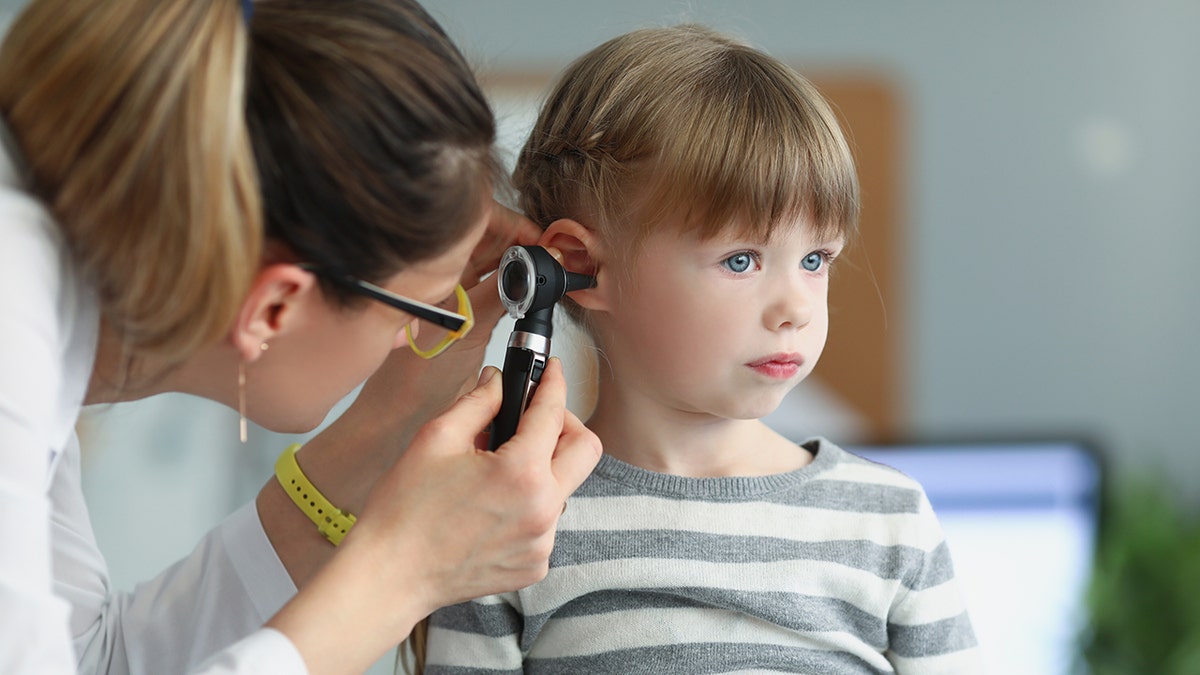 The doctor examines the ears of a little girl