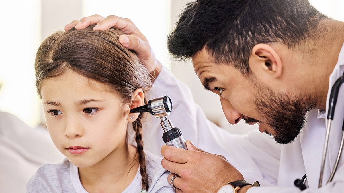 little girl has ears checked by doctor