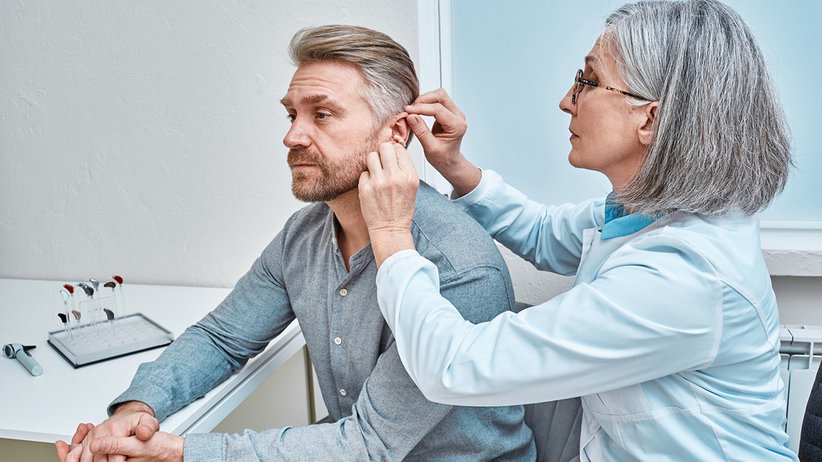 doctor inserts hearing aid