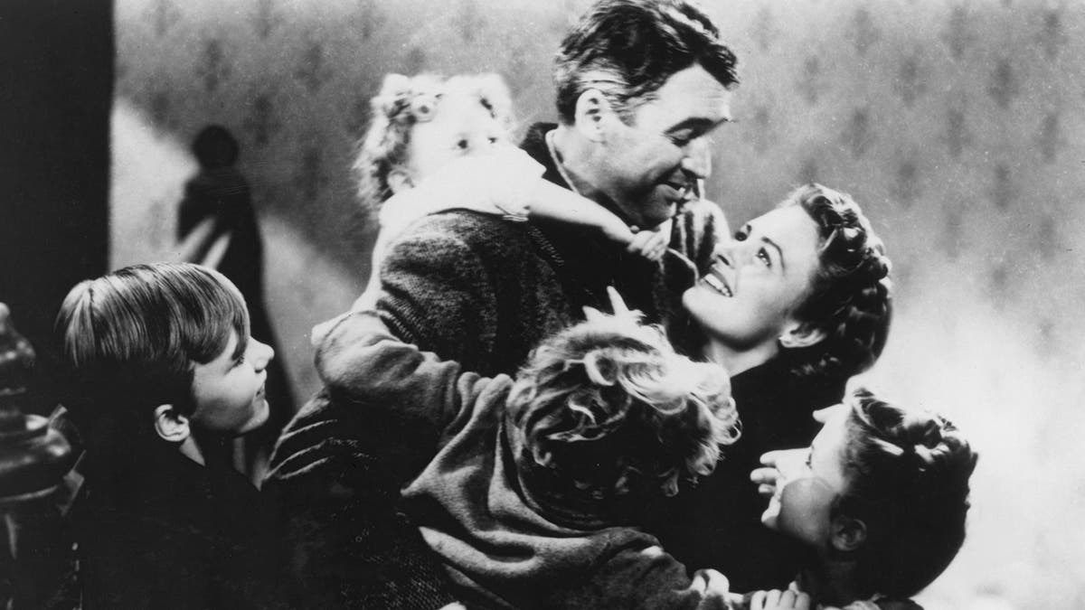 A black and white photo of James Stewart as George Bailey in "Its a Wonderful Life surrounded by his family, hugging