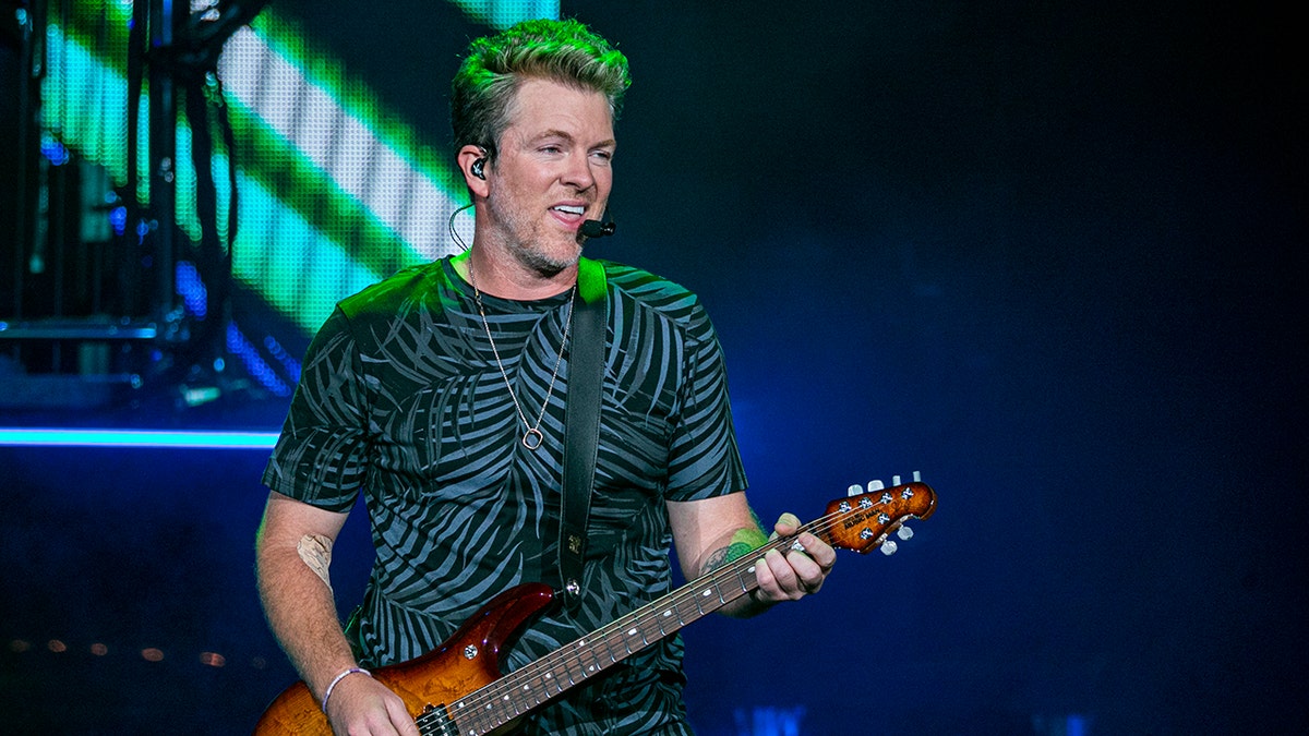 Joe Don Rooney in a printed shirt plays on the guitar on stage