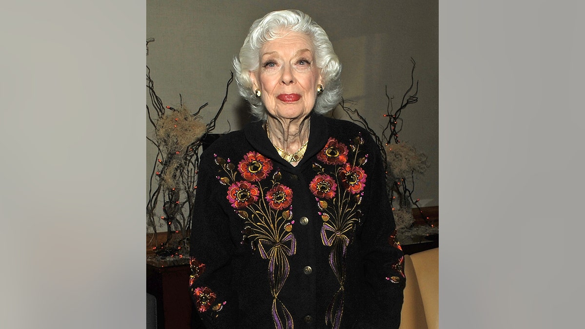 Joyce Randolph in a black shirt with flowers smiles for the camera
