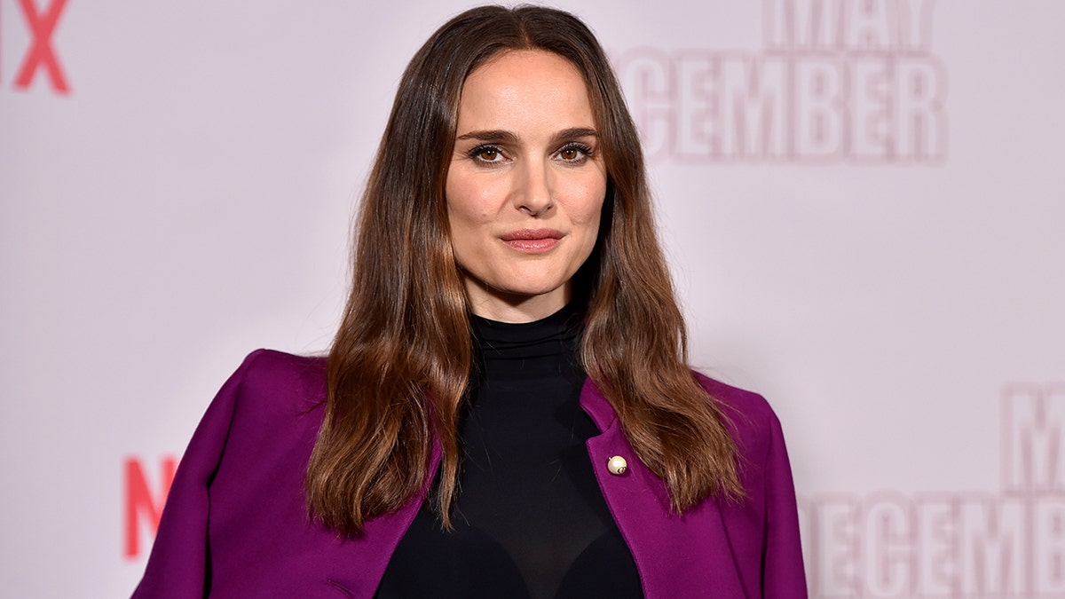 Natalie Portman in a plum colored jacket and black turtleneck on the carpet