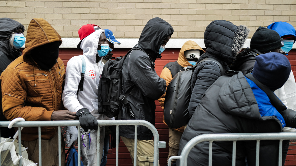 Migrants in line behind metal barricade in New York City