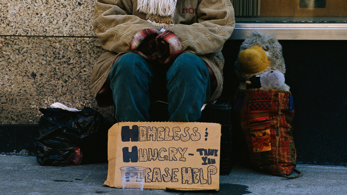 Homeless woman seated with cardboard "please help" sign