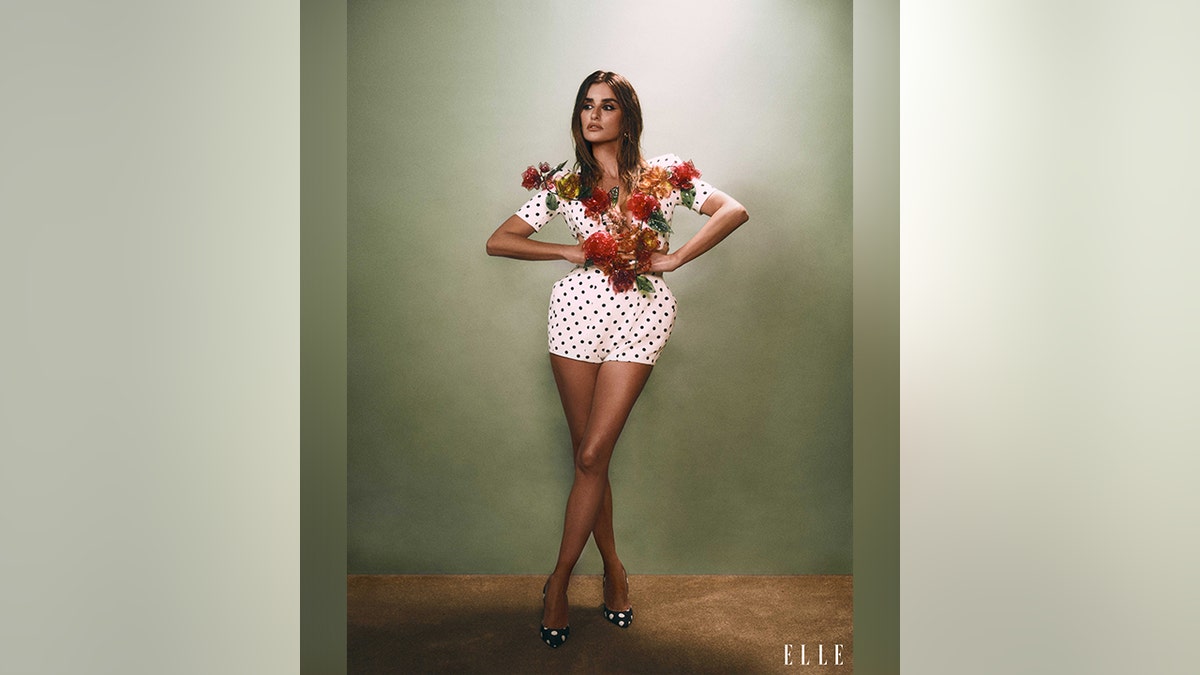 Penélope Cruz with a white polka dot outfit with flowers that go down the chest of the outfit.