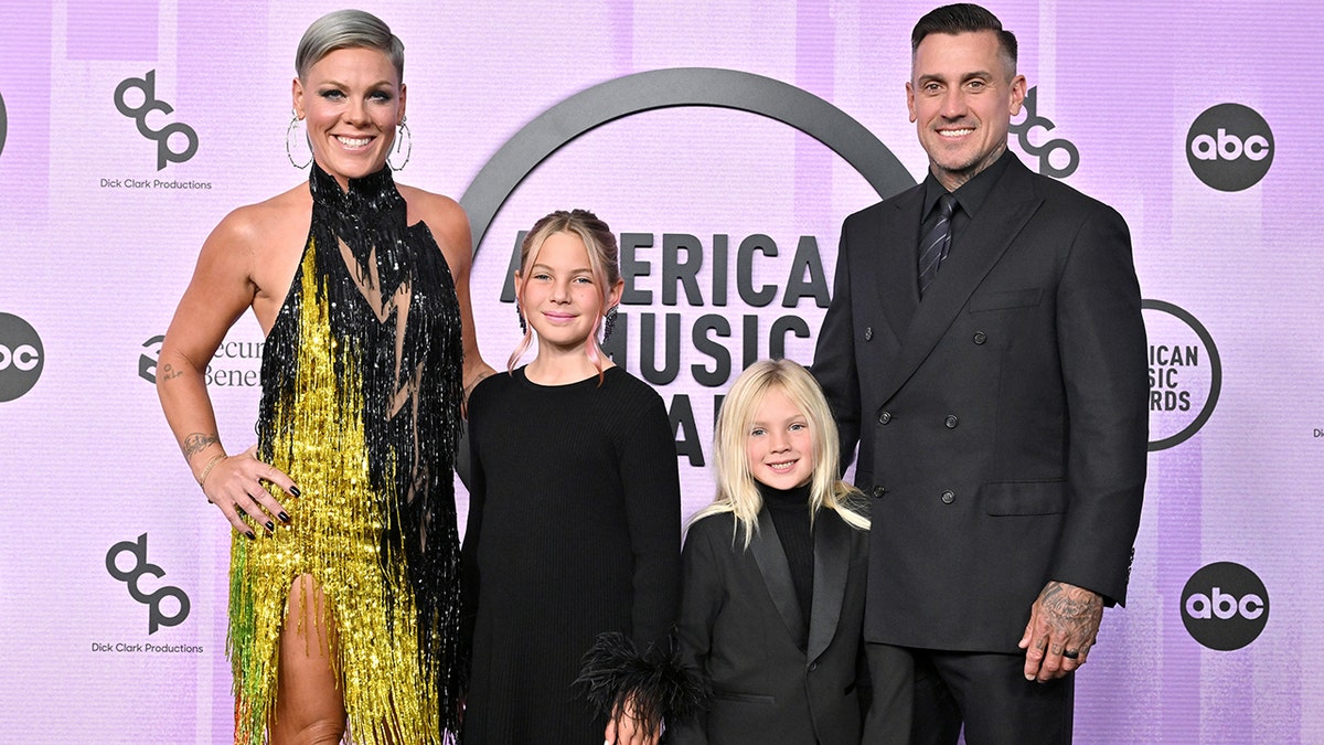 Pink in a yellow and black outfit with her kids Willow and Jameson and husband Carey Hart all in black at the AMAs