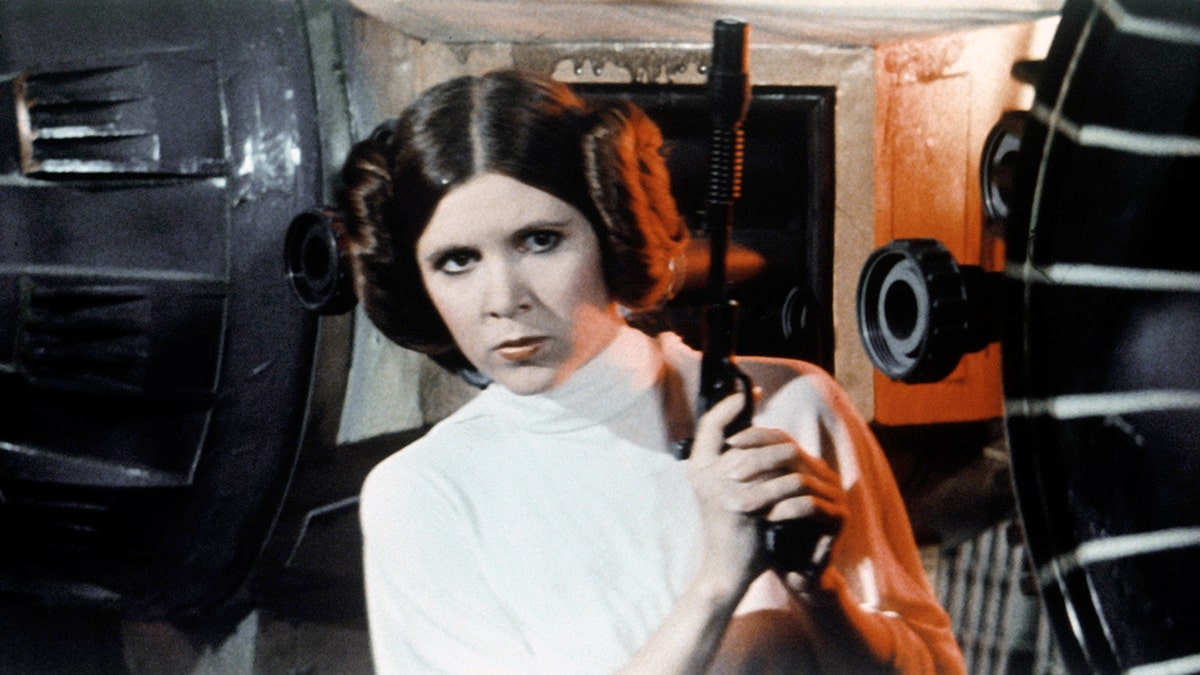 Carrie Fisher as Princess Leia in 'Star Wars' holding a weapon