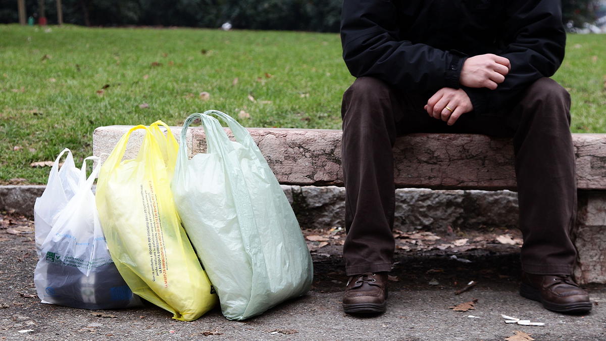 Man sitting next to plastic shopping bags 