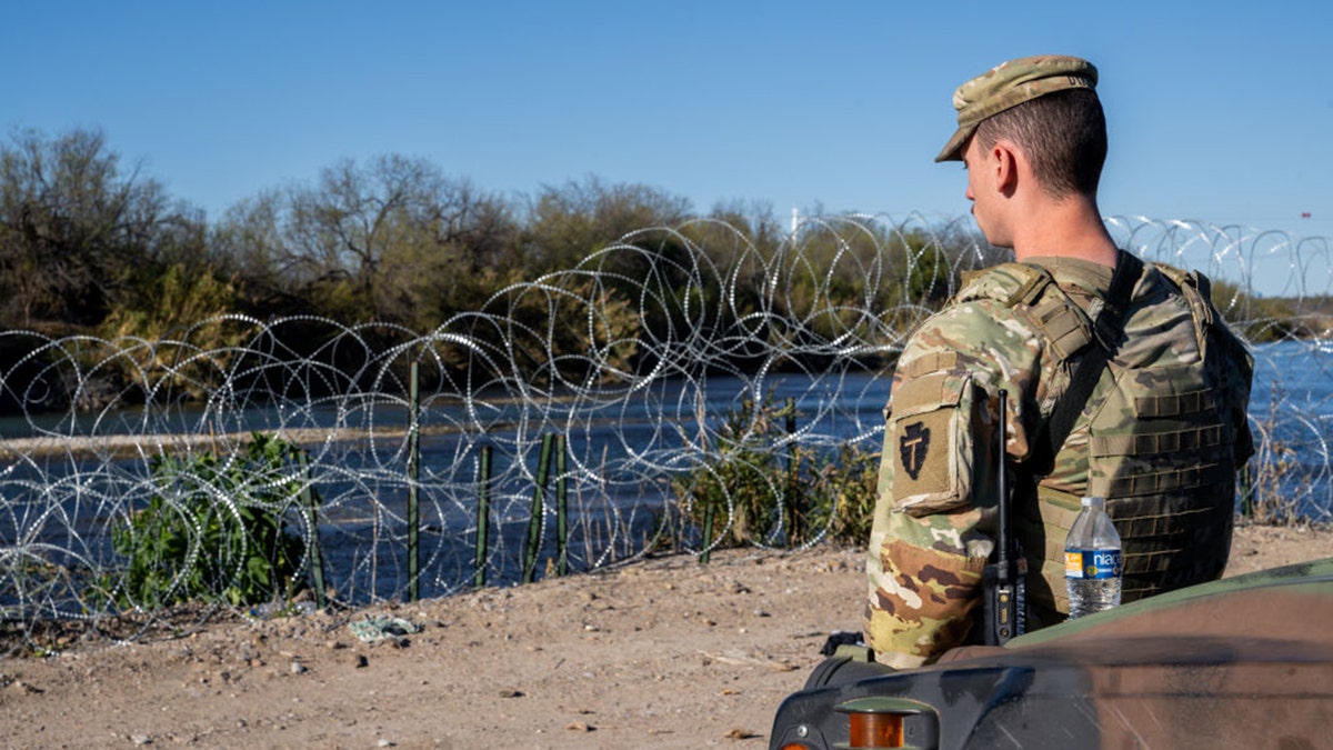 EAGLE PASS, TEXAS - JANUARY 12: A National Guard soldier stands guard on the banks of the Rio Grande river at Shelby Park on January 12, 2024 in Eagle Pass, Texas. 