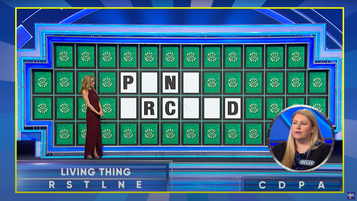 Vanna White stands at the board in a long maroon dress on "Wheel of Fortune"