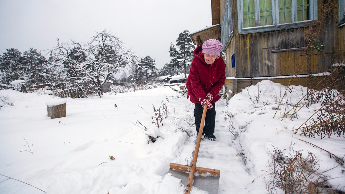 Elderly woman shoveling snow