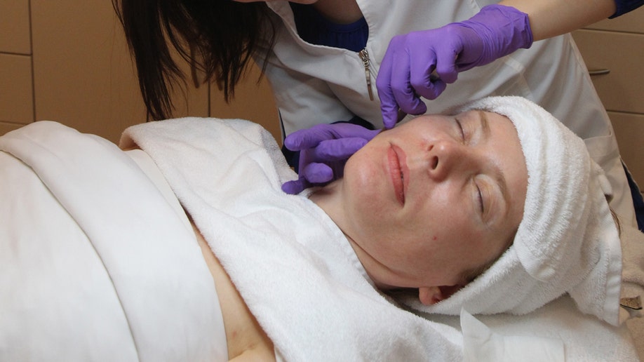 Woman does dermaplaning during her facial