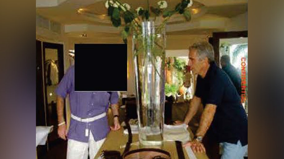 A partially-redacted evidence photo shows Jeffrey Epstein alongside a male friend on Little St. James Island