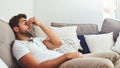 Cropped shot of a handsome young man holding his nose while lying on a couch at home during the day