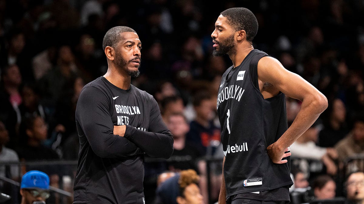 Kevin Ollie talks to players during a Nets game