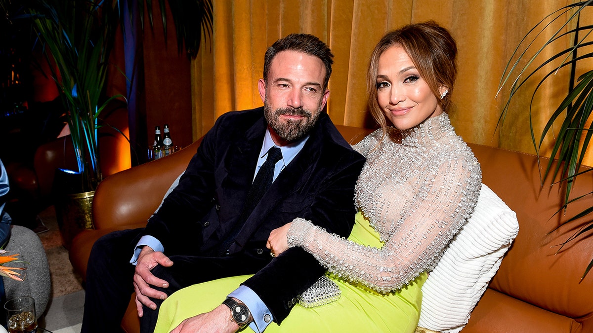 Ben Affleck and Jennifer Lopez sitting on a couch together