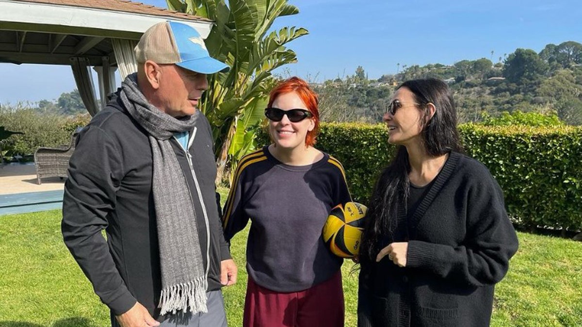 Bruce Willis, Tallulah Willis, and Demi Moore standing in a yard together