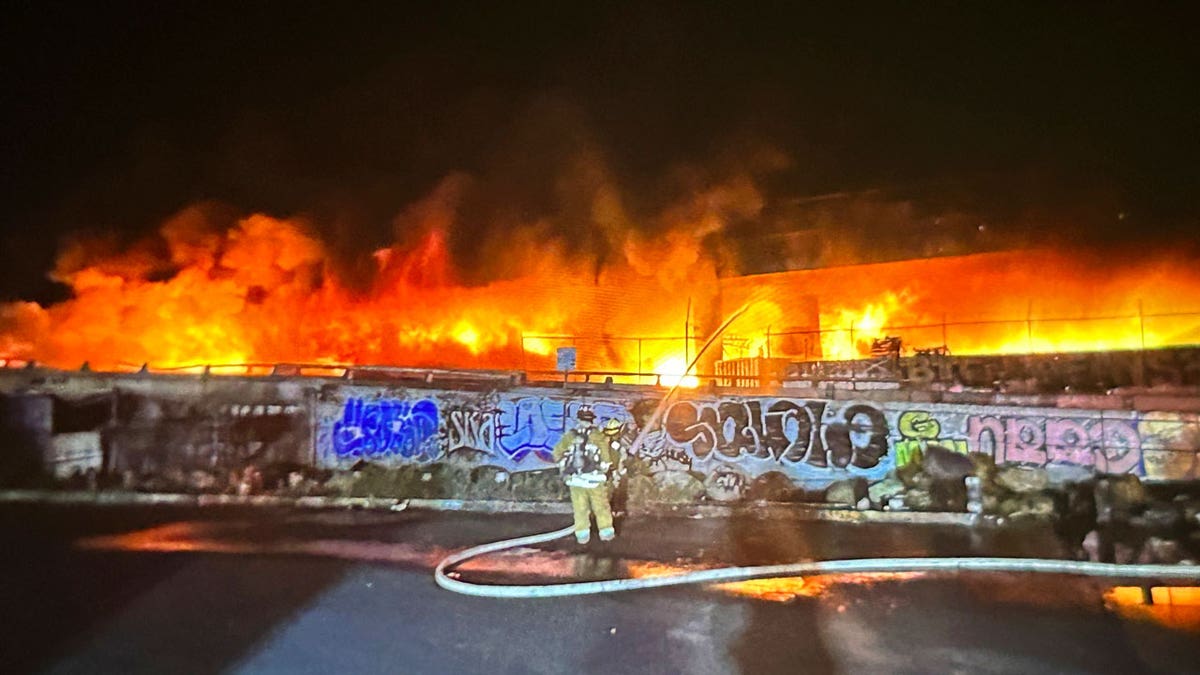 Firefighters spray water onto a fire along Interstate 10