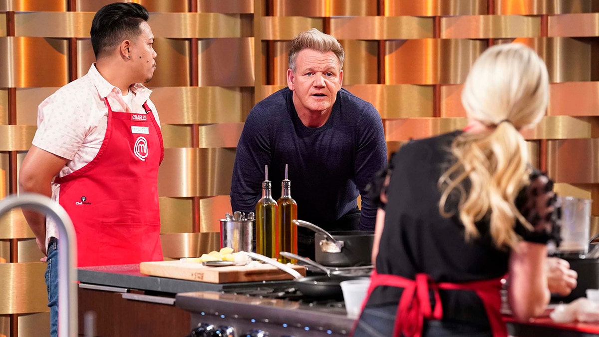 Gordon Ramsay in a blue shirt leans over a stove on "MasterChef"