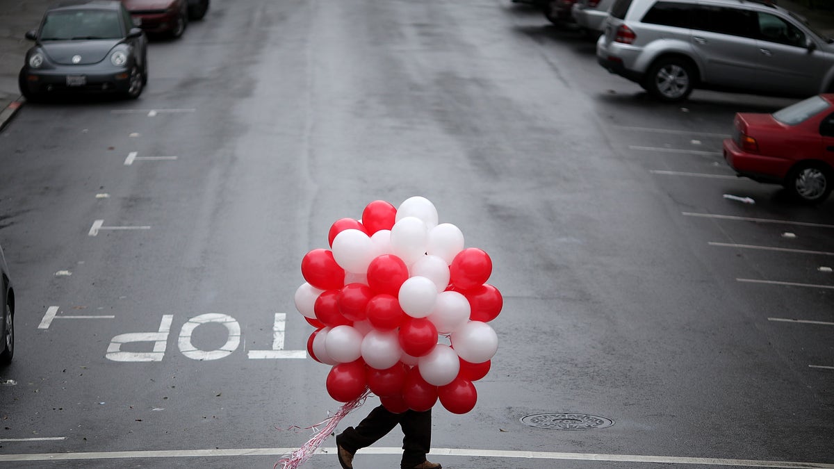 A man carries red and white balloons on Valentine's Day.