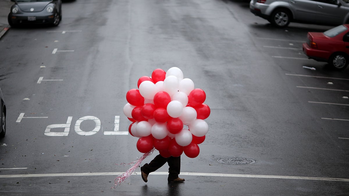 A man carries red and white ballons on Valentine's Day