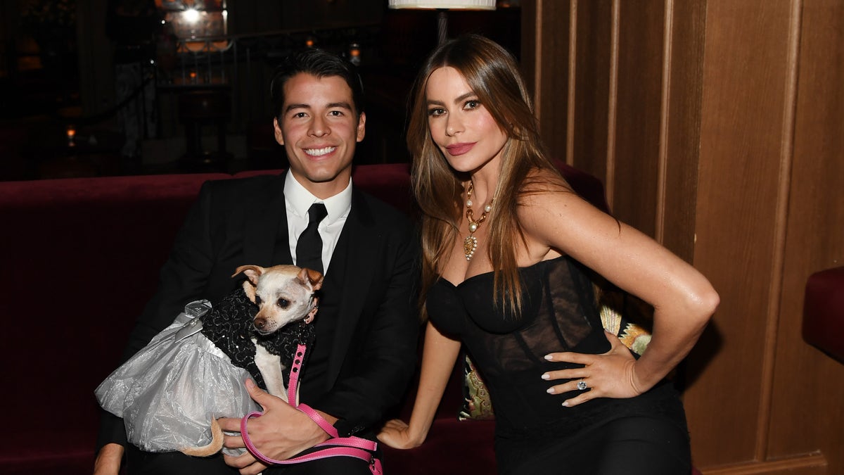 Sofía Vergara sitting on a sofa with her son Manolo and her dog.
