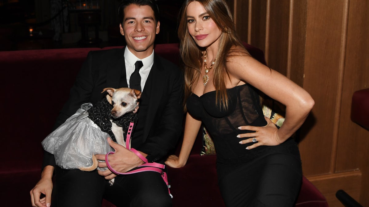 sofia vergara sitting on a couch with her son manolo and their dog