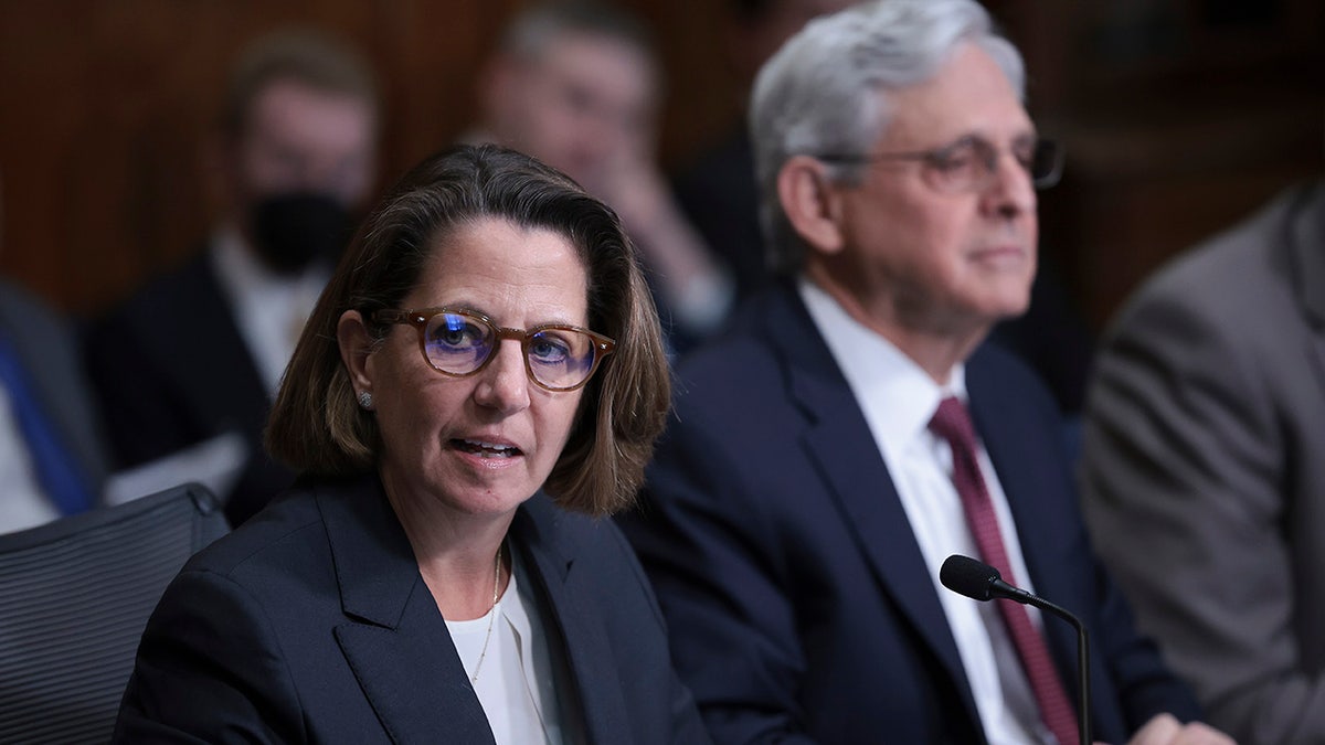 Lisa Monaco seated next to Garland during a DC crime presser