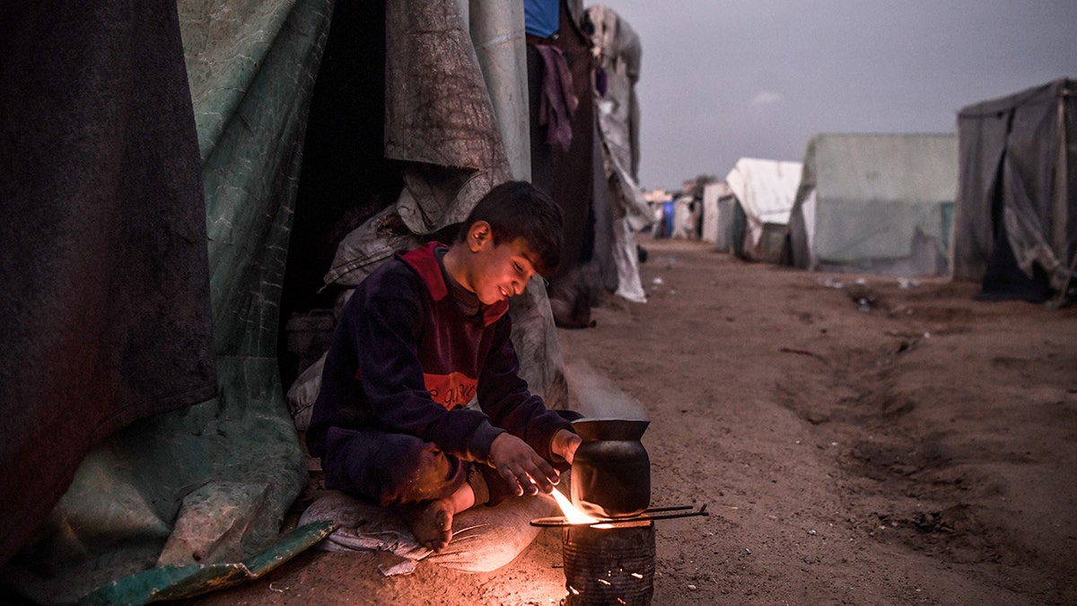 A Palestinian boy sits by the tent.