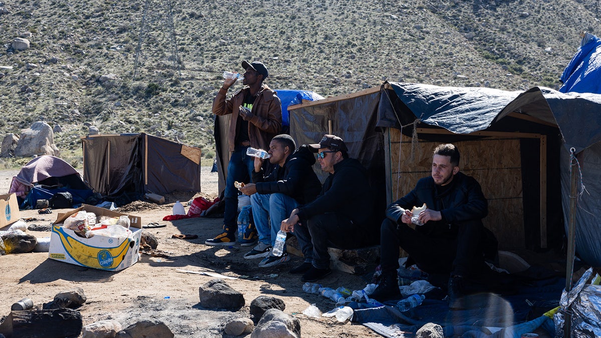 Migrants drink water at makeshift camp outside San Diego